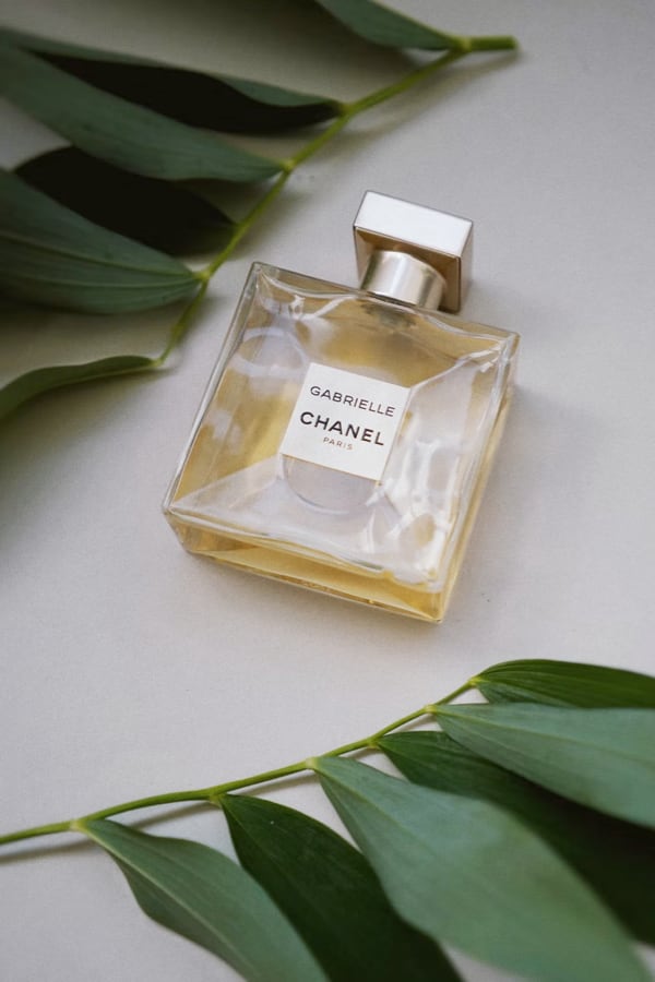 picture of Gabrielle Essence Eau De Parfum laying on its back with green leafs in the background